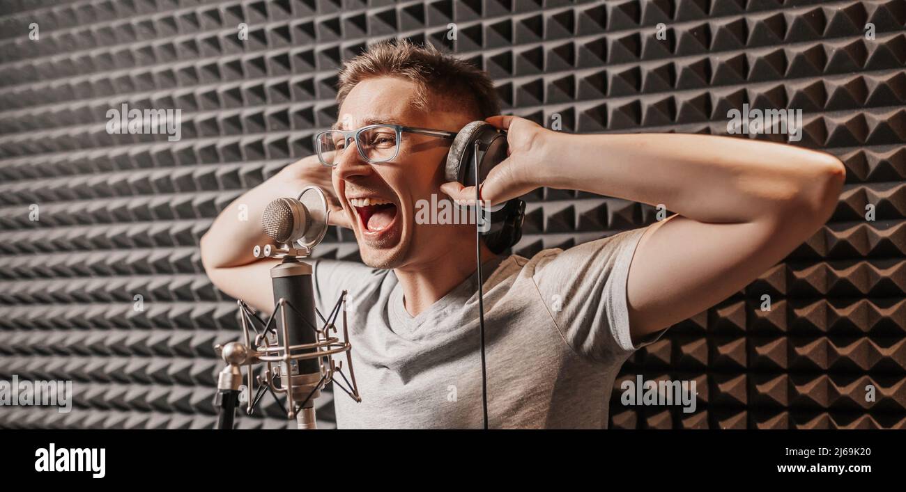 Il cantante canta in studio in un microfono. L'uomo in cuffia scrive un podcast, un audiolibro. Artista, registrazione di un album, utilizzo dell'etichetta Foto Stock