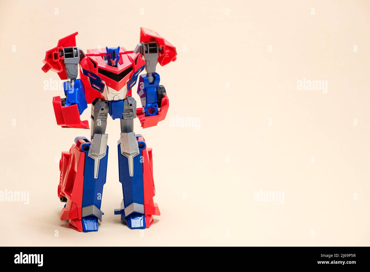 Robot rosso e blu su sfondo beige con spazio per il testo. Giocattoli per bambini, negozio di giocattoli Foto Stock