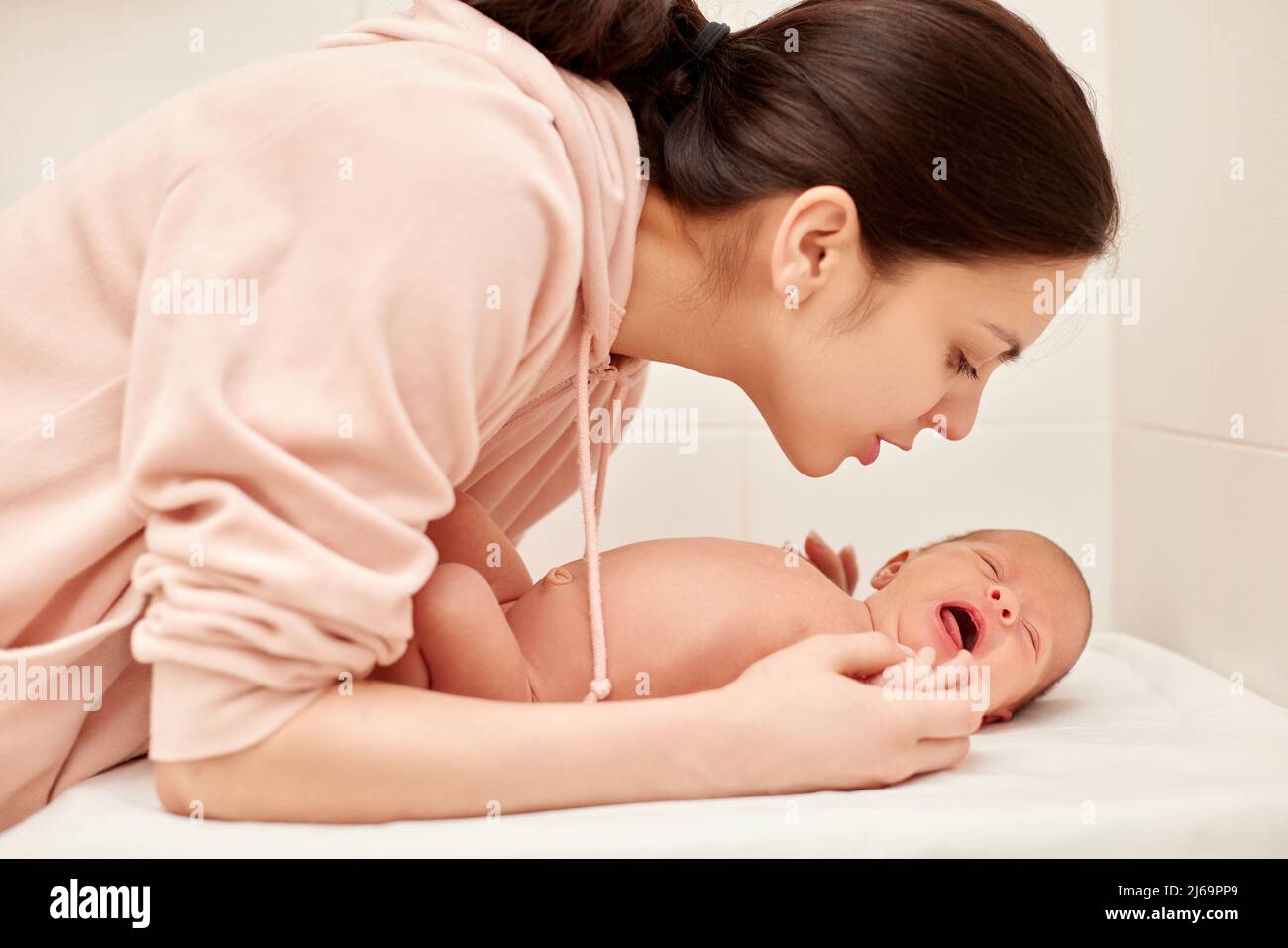 La giovane madre bacia il suo bambino neonato carino Foto Stock