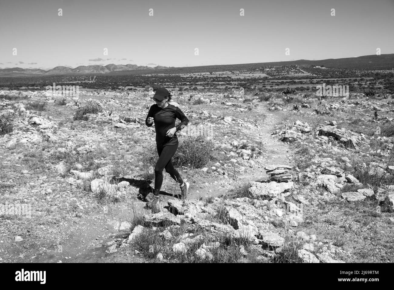 Donna che indossa un sentiero nero che corre su un terreno roccioso Foto Stock