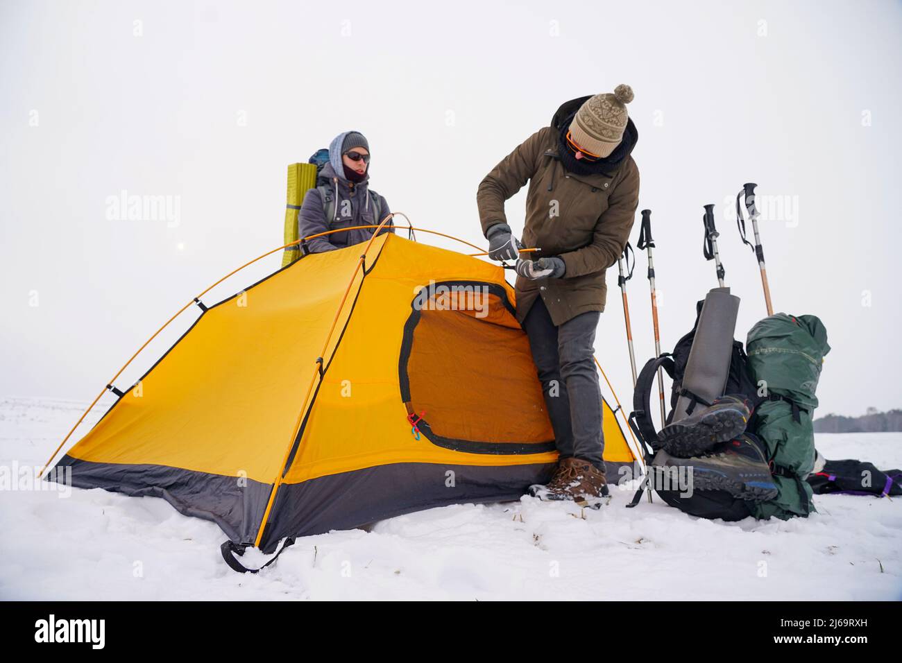 Due ragazzi stanno creando una tenda nella neve. Installazione di una tenda durante una spedizione invernale in condizioni estreme. Trekking invernale Foto Stock