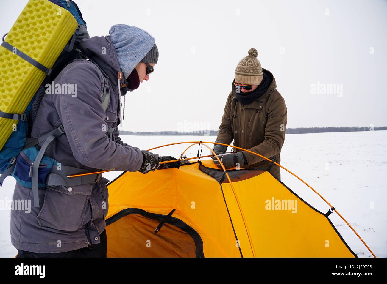 Due ragazzi stanno creando una tenda nella neve. Installazione di una tenda durante una spedizione invernale in condizioni estreme. Trekking invernale Foto Stock