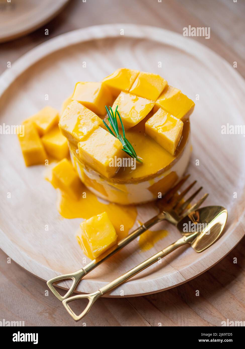 Cheesecake al Mango giallo dolce su vassoio di legno rotondo Foto Stock