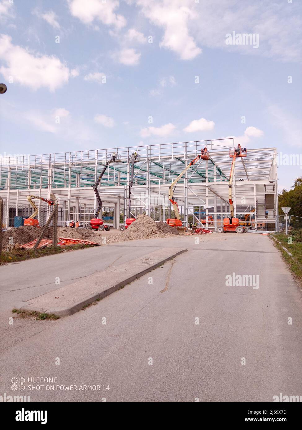 Un moderno edificio per uffici in costruzione con un pilone elettrico in primo piano Foto Stock