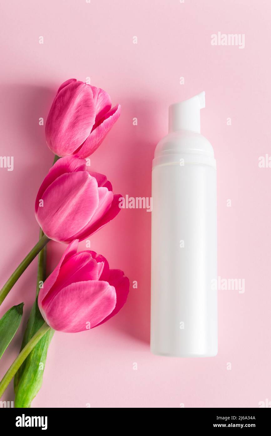 Prodotti per la cura della pelle Spa su sfondo rosa. Cosmetici naturali e tulipani rossi. Posiziona per il testo. Foto Stock