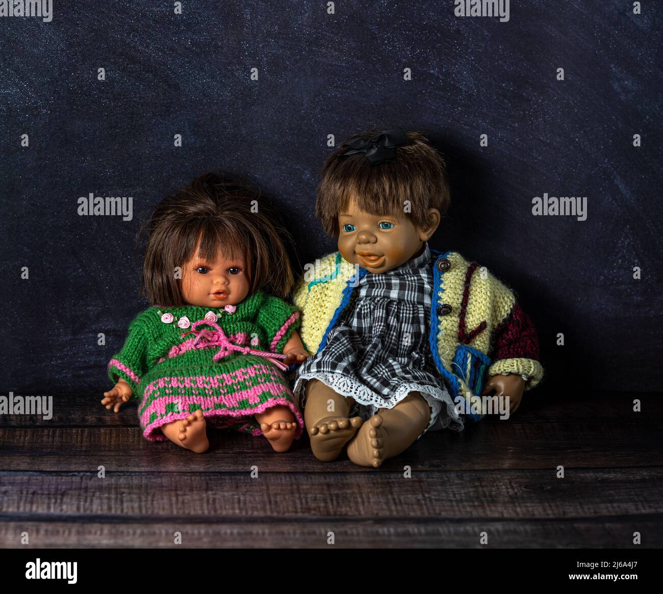 Due bambole d'epoca incredibilmente realistiche: Con occhi blu e marroni. Le bambole sono vestite con colorati abiti a maglia. Messa a fuoco selettiva. Coppia. Foto Stock