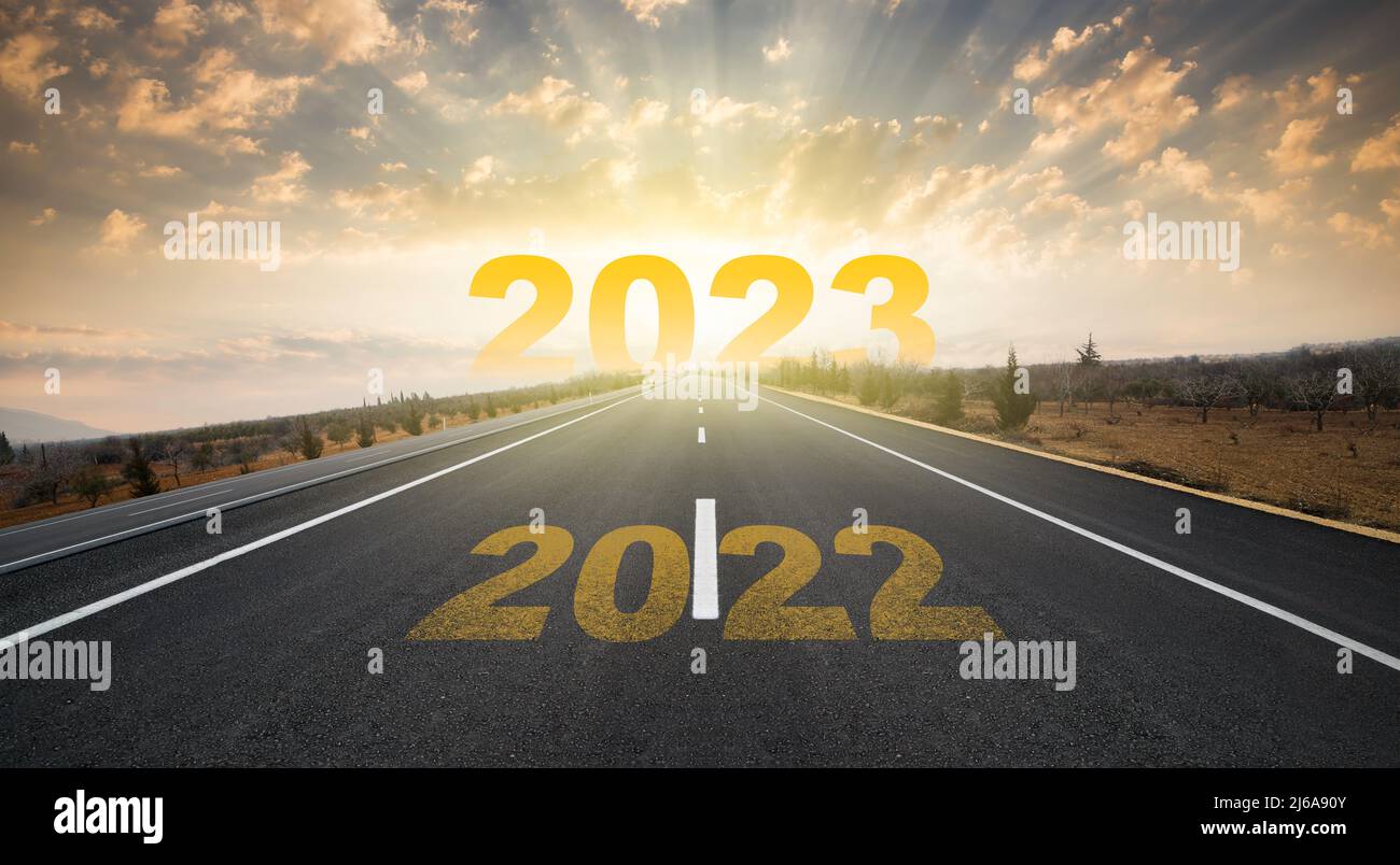 2023° anniversario. Transizione dal 2022 al nuovo anno. Alba dorata su strada asfaltata vuota. Concetto di nuovo anno con il numero 2023 all'orizzonte. Foto Stock