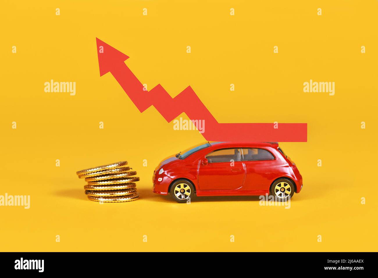 Piccola auto con freccia crescente e monete in denaro su sfondo giallo Foto Stock