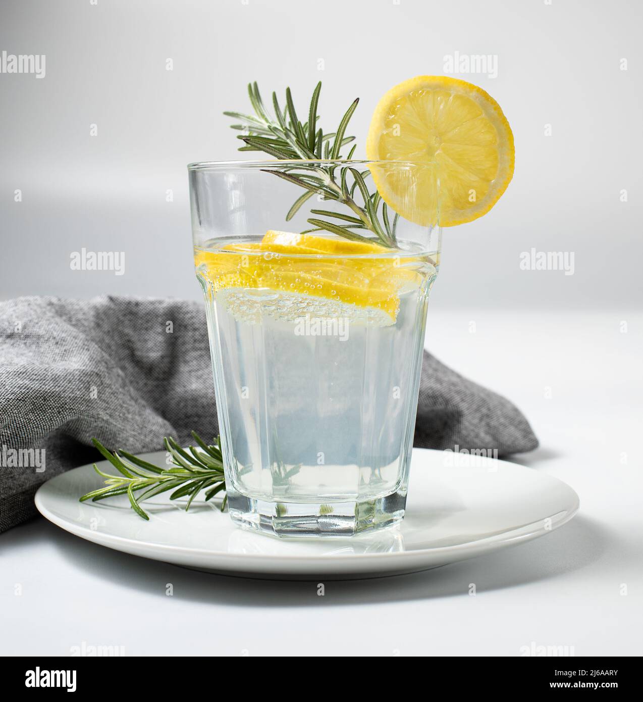 Bicchiere con acqua fresca di limone o limonata fatta in casa e rosmarino su sfondo bianco, foto di scorta Foto Stock