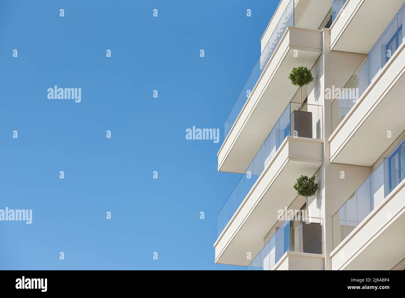 Balcone con ringhiera di vetro in un moderno edificio di appartamenti contro un cielo blu con uno spazio copia Foto Stock