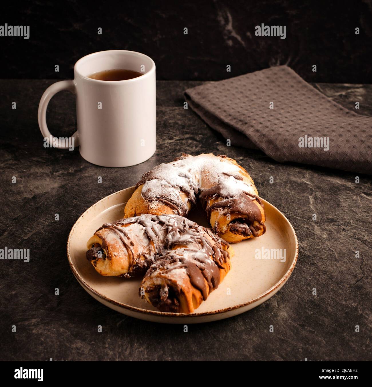 Tazza di tè nero e dolci al cioccolato tradizionali, tessuti su sfondo scuro, foto di scorta Foto Stock