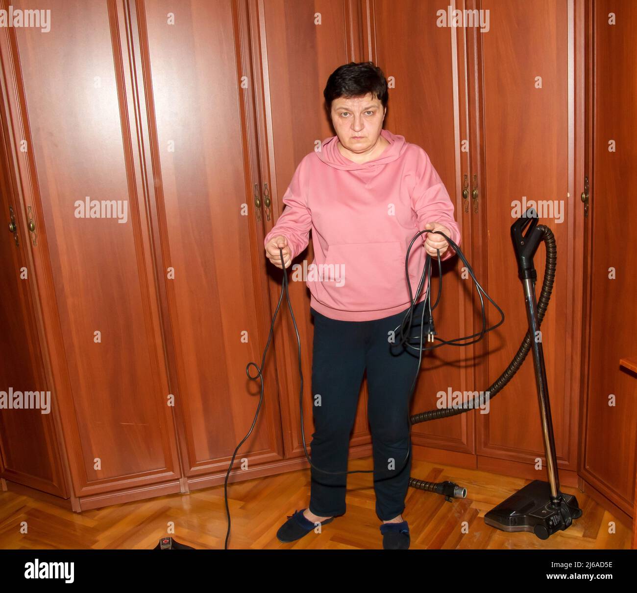 Una donna di mezza età raccoglie un aspirapolvere per la pulizia della casa. Foto Stock