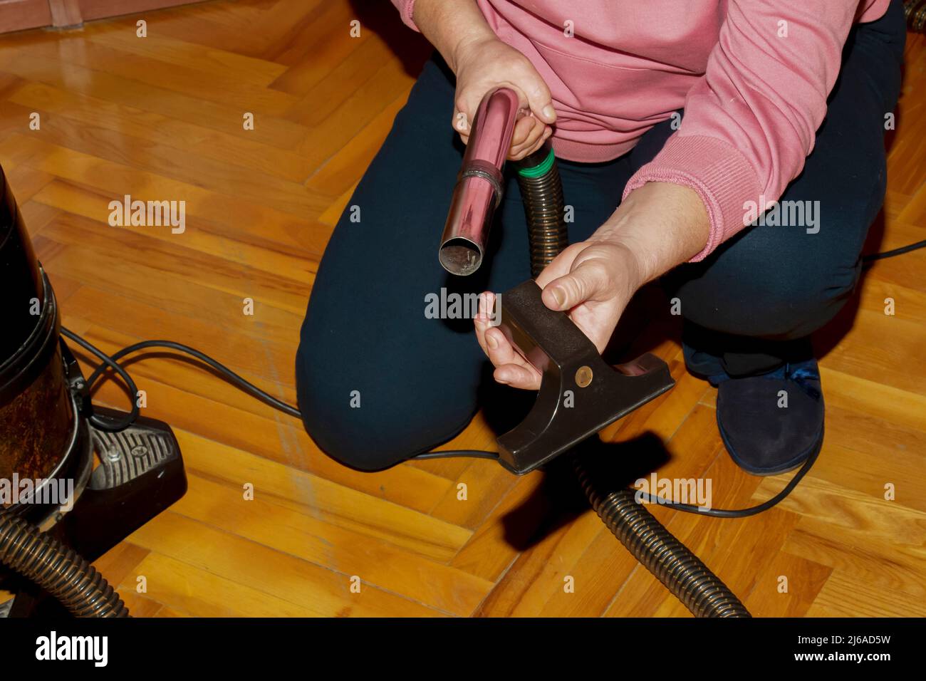 Una donna di mezza età raccoglie un aspirapolvere per la pulizia della casa. Foto Stock