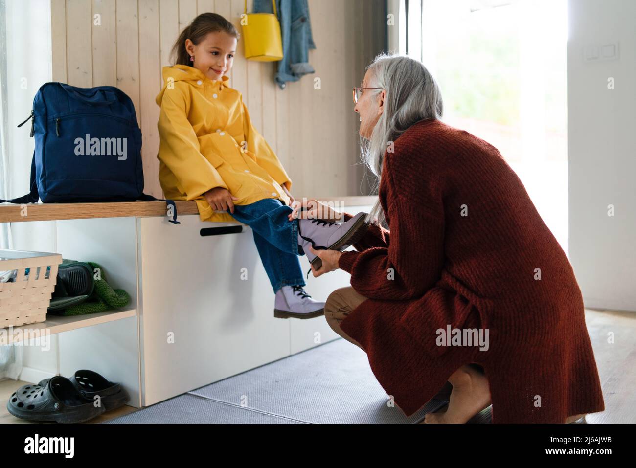 Nonna che aiuta la nonna a prepararsi a lasciare a casa per la scuola. Foto Stock