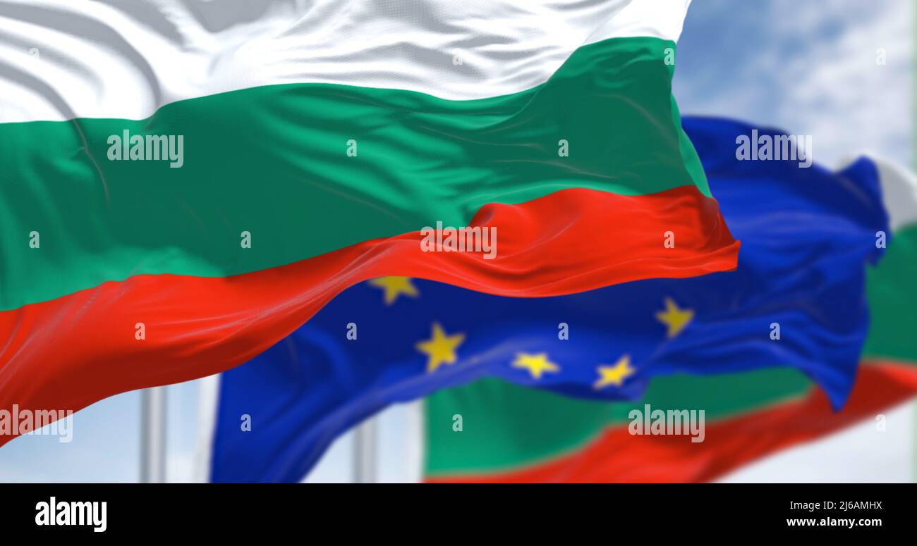Dettaglio della bandiera nazionale della Bulgaria che sventola nel vento con la bandiera dell'Unione europea sfocata sullo sfondo in una giornata chiara. Democrazia e politica. Foto Stock