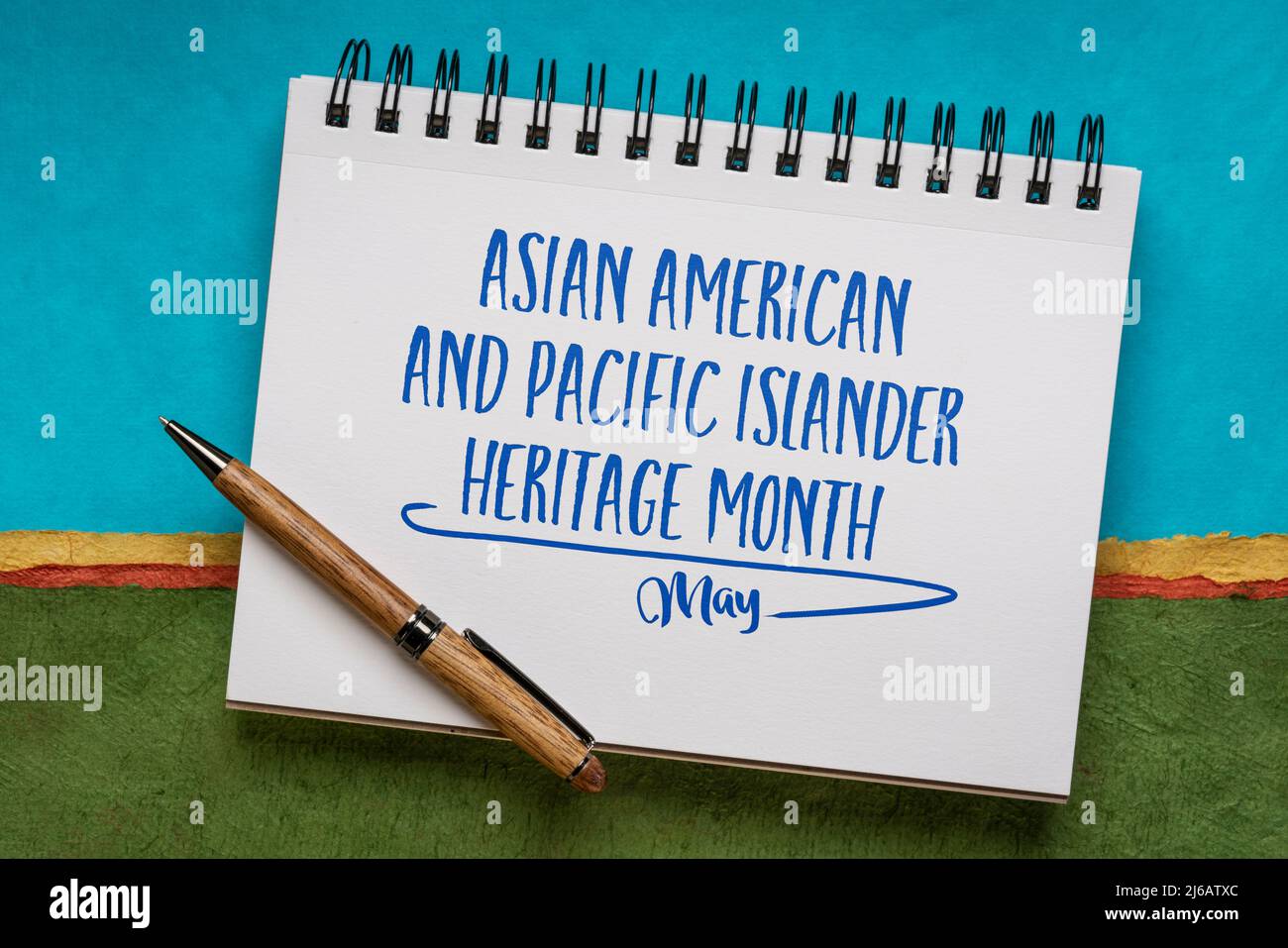 Asian American and Pacific Islander Heritage Month, maggio - scrittura a mano in un libro di schizzo contro il paesaggio astratto, ricordo di evento culturale Foto Stock