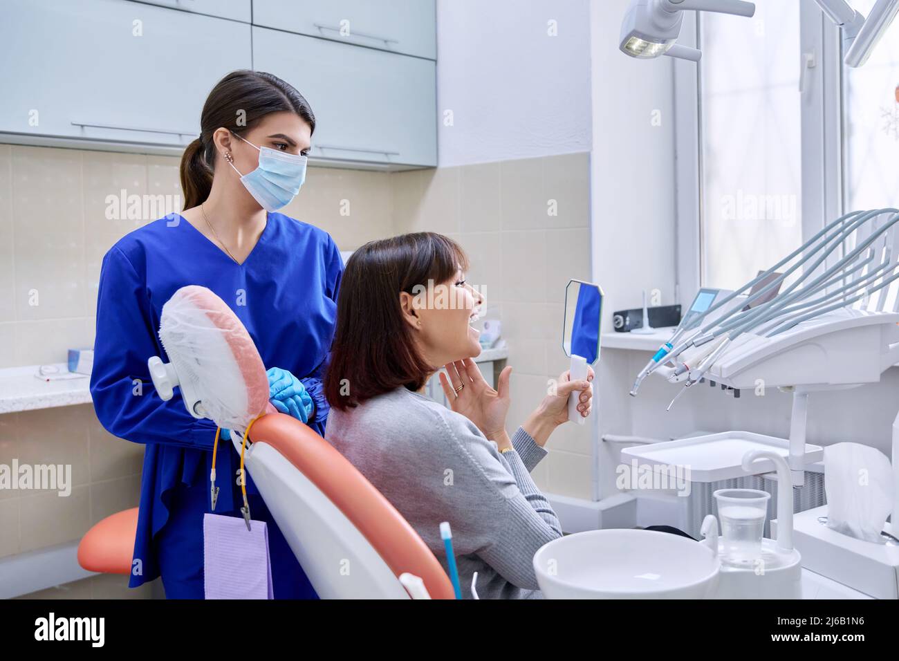 Studio del dentista, paziente donna che guarda i denti nello specchio Foto  stock - Alamy