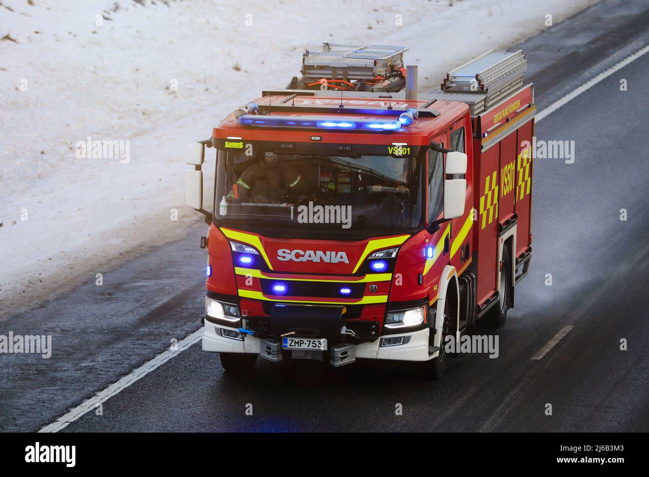 Scania P CrewCab camion antincendio a chiamata con luci blu lampeggianti, a velocità in autostrada in un giorno d'inverno. Salo, Finlandia. Dicembre 31, 2021. Foto Stock