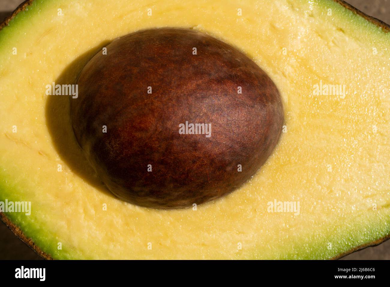 Mezza avocado macro, primo piano. Frutta cruda sano cibo verde. Avocado su sfondo in legno. Foto Stock