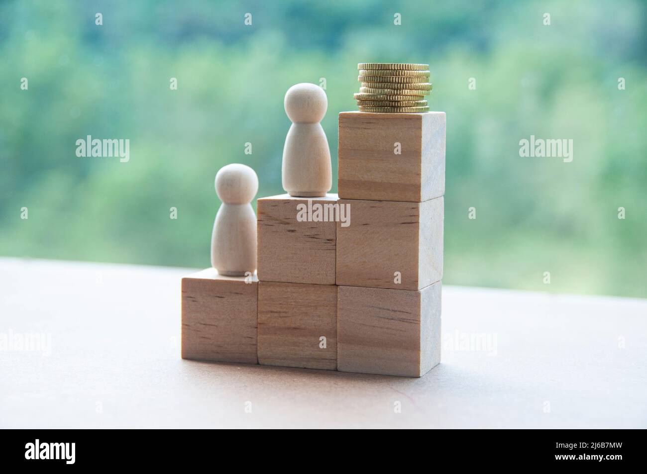 Bambole in legno e monete d'oro sopra i blocchi di legno impilati. Obiettivo raggiungere il concetto e lo spazio di copia Foto Stock