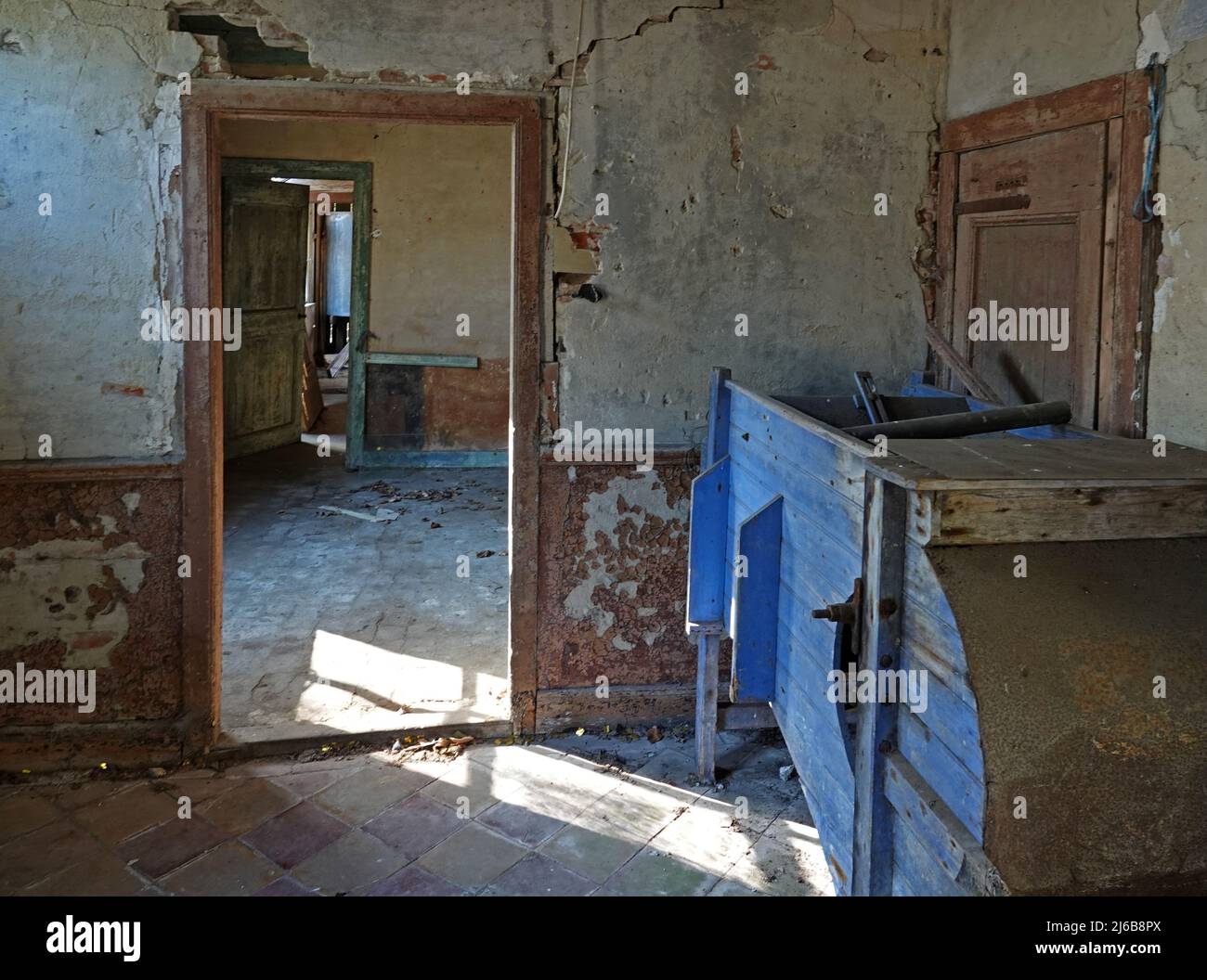 Vecchi spazi dilapidati. La luce del sole splende attraverso la finestra. Potete vedere le seguenti stanze attraverso le porte. Buchi nella parete. Un luogo perduto Foto Stock