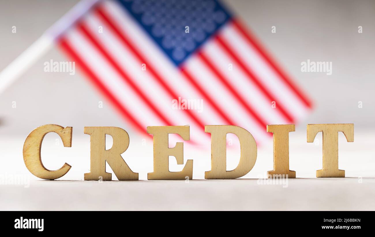 Testo di lettere in legno e la bandiera americana su uno sfondo astratto, il concetto di un prestito dagli Stati Uniti. Foto Stock