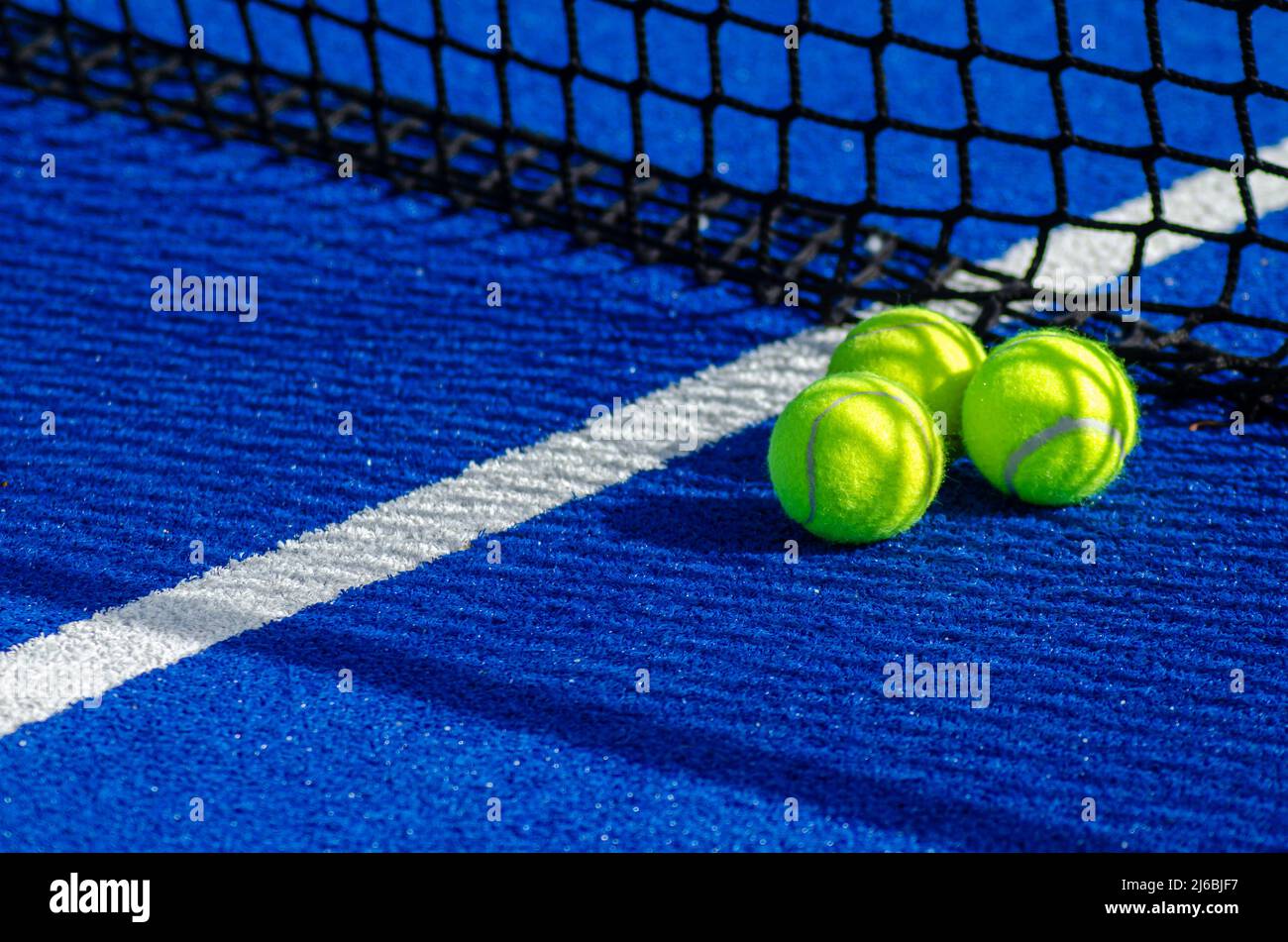 Tre palle vicino alla rete di un campo da tennis in padel blu, concetto di sport racket Foto Stock