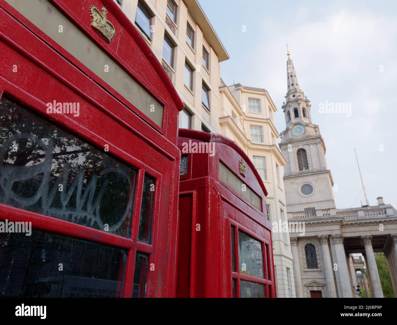 Primo piano immagine astratta delle scatole telefoniche rosse con la Corona reale con una St Martins fuori fuoco nella chiesa Fields dietro. Foto Stock