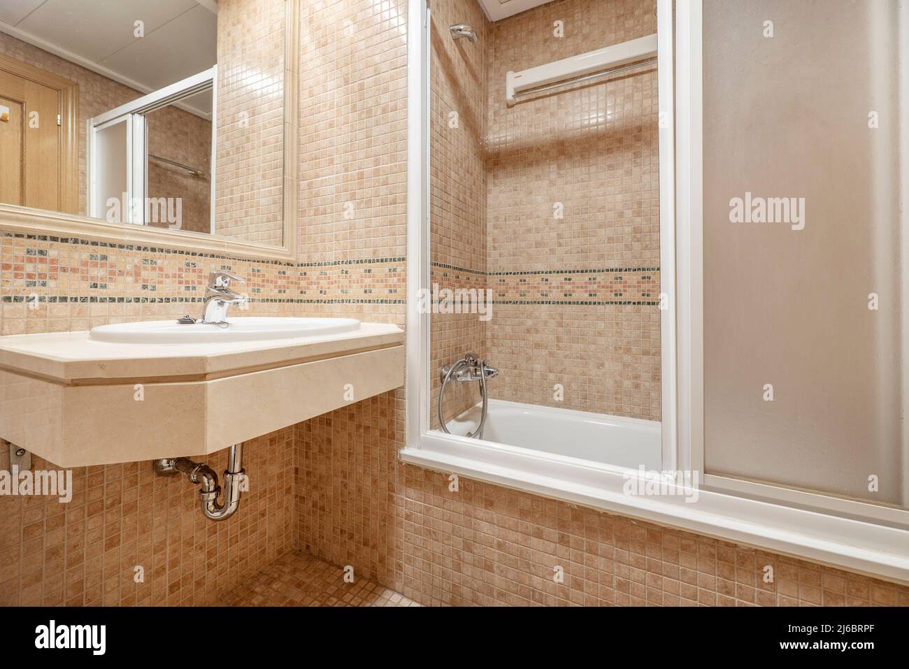 Bagno con lavello in porcellana sospeso sul piano in marmo, piastrelle in  mosaico sulle pareti, rubinetti cromati, specchio da incasso e cabina  doccia con scre bianco Foto stock - Alamy