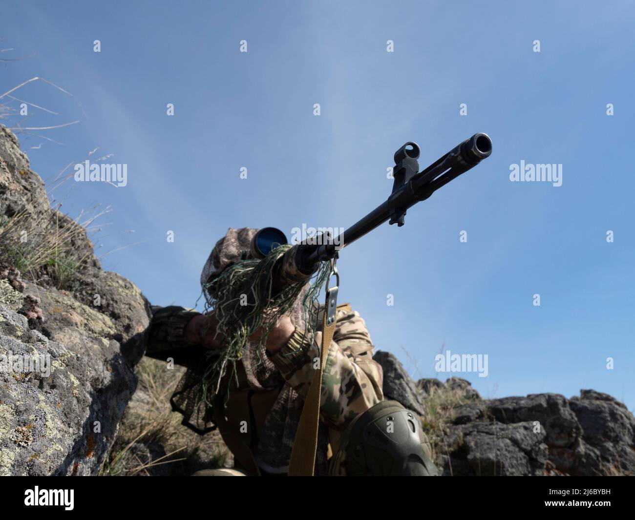 Un'imboscata in montagna - cecchino professionale delle forze speciali durante un'operazione speciale che mira al nemico. Concetto di operazioni militari moderne e. Foto Stock