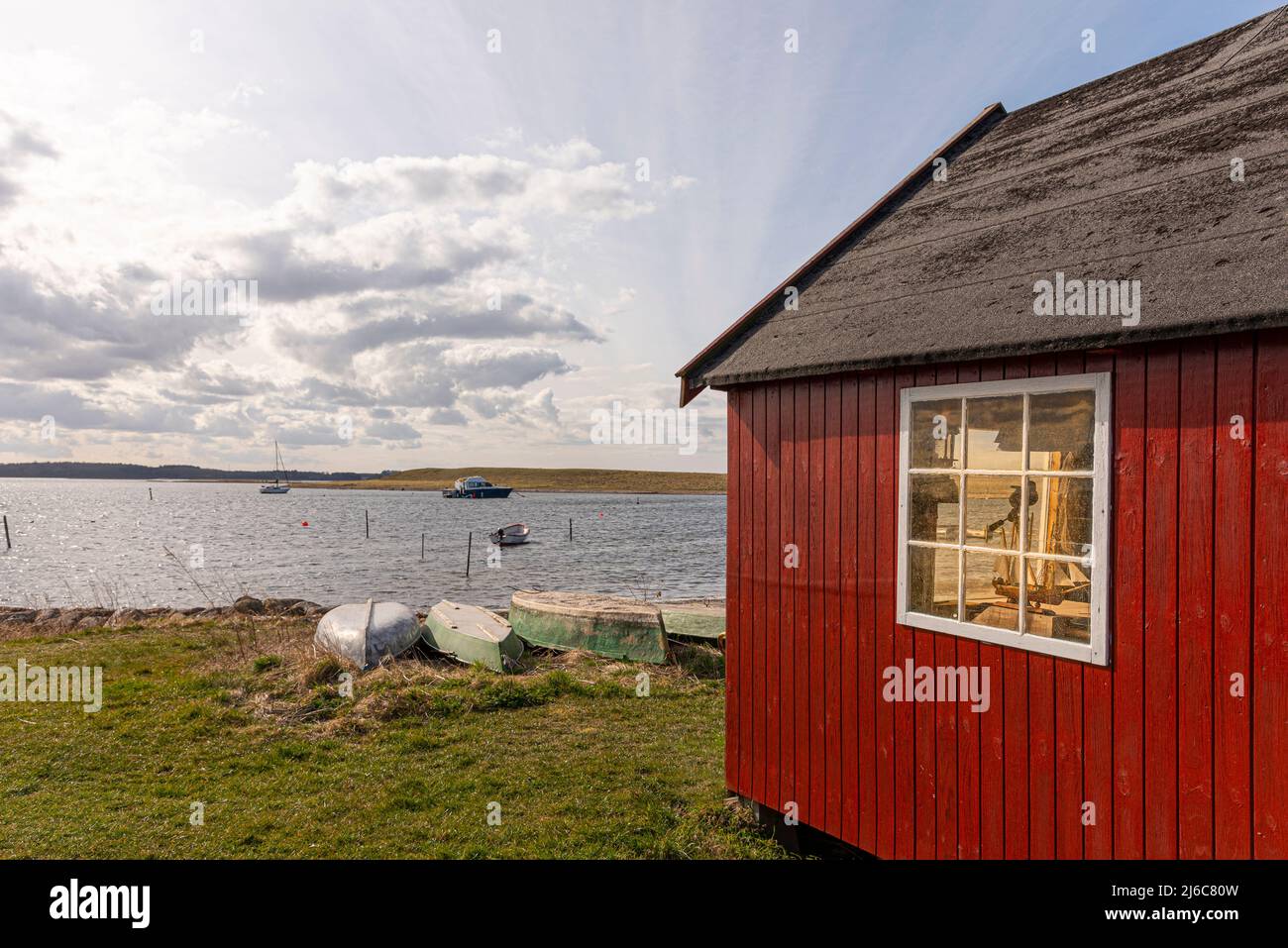 Una capanna rossa di pescatori sulla riva con il sole attraverso la finestra a Jyllinge, Danimarca, 29 marzo 2022 Foto Stock