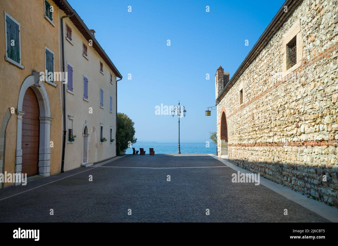 Italia, Lazise, una strada che porta alla riva del lago con il vecchio edificio custom sulla destra Foto Stock