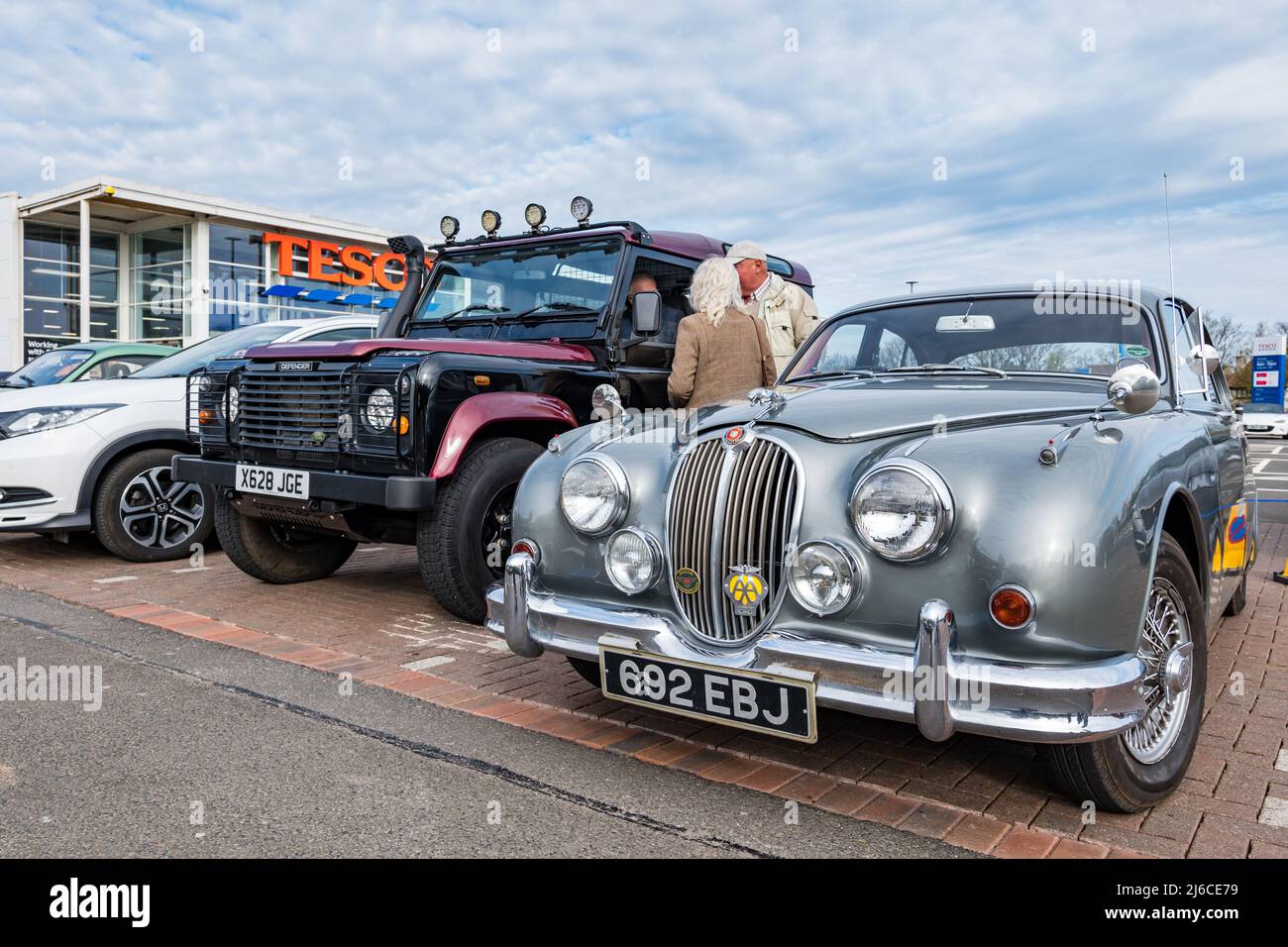 Auto Jaguar Vintage 1960 e Land rover Defender al rally classico, parcheggio supermercato Tesco, North Berwick, East Lothian, Scozia, REGNO UNITO Foto Stock