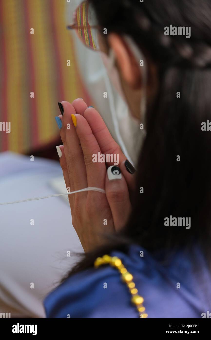 Matrimonio tailandese: Una bridesmaid prega mentre tiene una stringa di significato religioso, che simboleggia il desiderio di felicità Foto Stock
