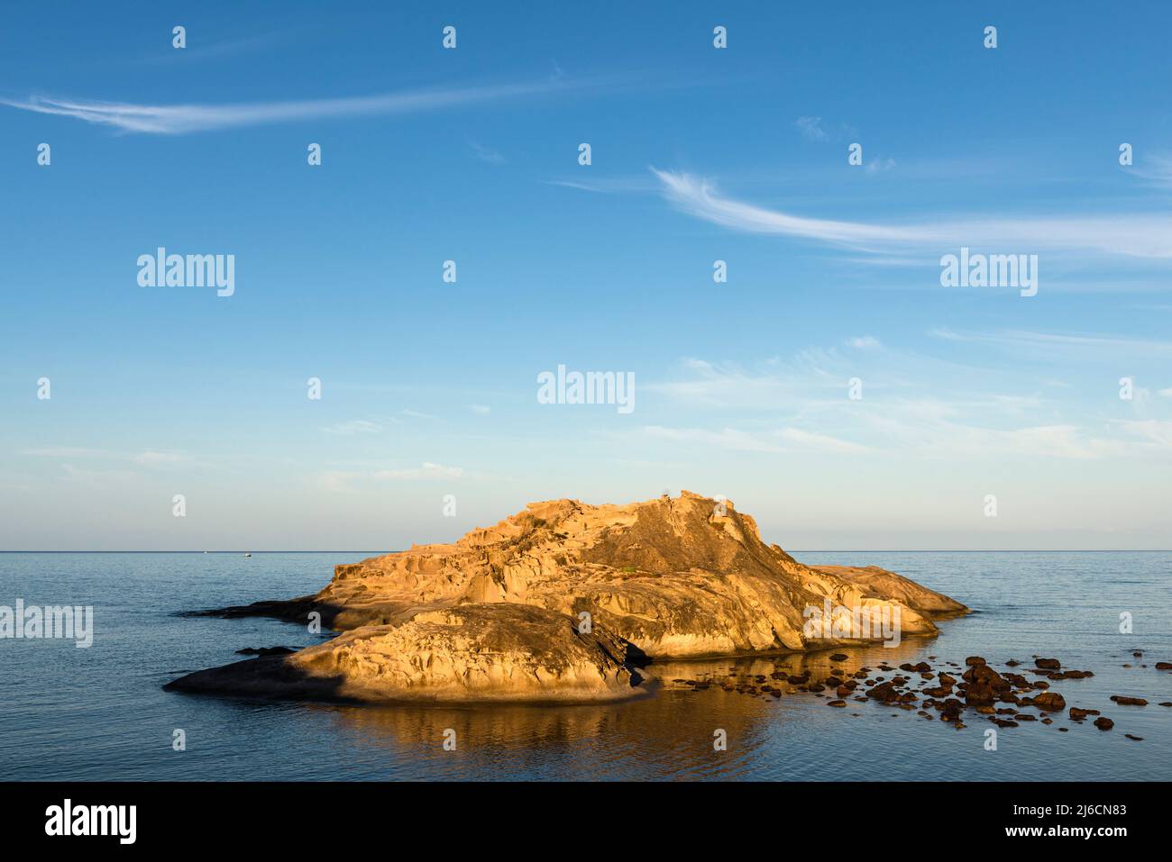 Fascino sardo - due nuvole di cirro su un'isola rocciosa nella baia di Torre Argentario sulla costa occidentale al sole mattutino, Sardegna, Italia, Europa Foto Stock