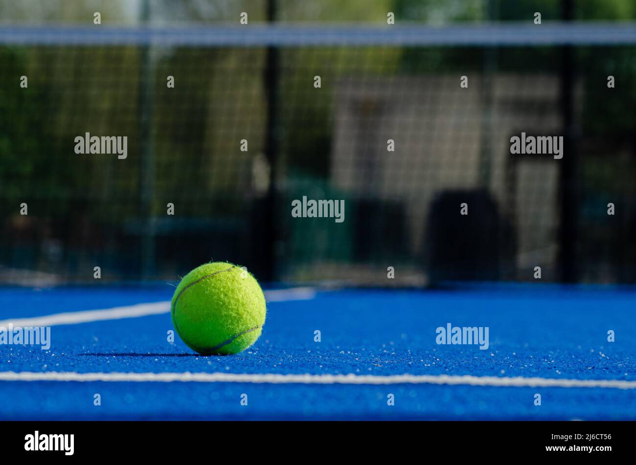 Paddle da tennis su un campo blu con la rete fuori fuoco sullo sfondo. Foto Stock