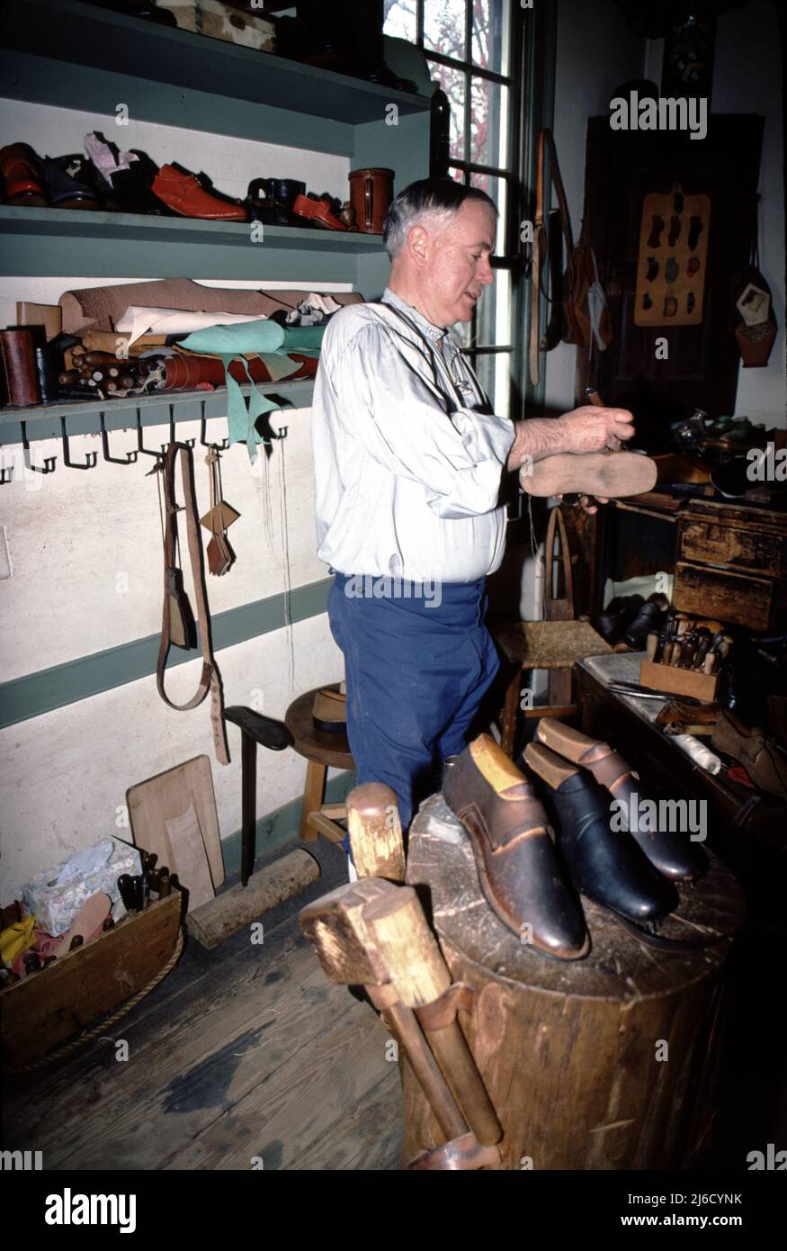 Williamsburg, California. USA 9/1987. Cordwainer era il titolo dato ai calzolai. Cobblers erano quelli che riparavano le scarpe. Il cobbler aveva cinque anni di formazione in meno rispetto ad un cordwainer. Nella maggior parte dei paesi, comprese le colonie americane, i ciottoli sono stati proibiti proclamando di fare scarpe. I primi calzolai, conciatori e altri commercianti arrivarono a Jamestown nel 1607; tra i molti talenti del fondatore principale della colonia John Smith, era quello del calzolaio – l’insediamento era parzialmente finanziato da un fiorente commercio di scarpe inglese. Foto Stock