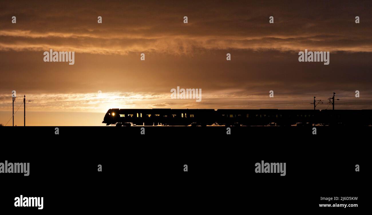 Treno Northern Rail / Northern Trains CAF Civity classe 195 treno sulla costa occidentale linea principale al tramonto che rende una silhouette. Foto Stock