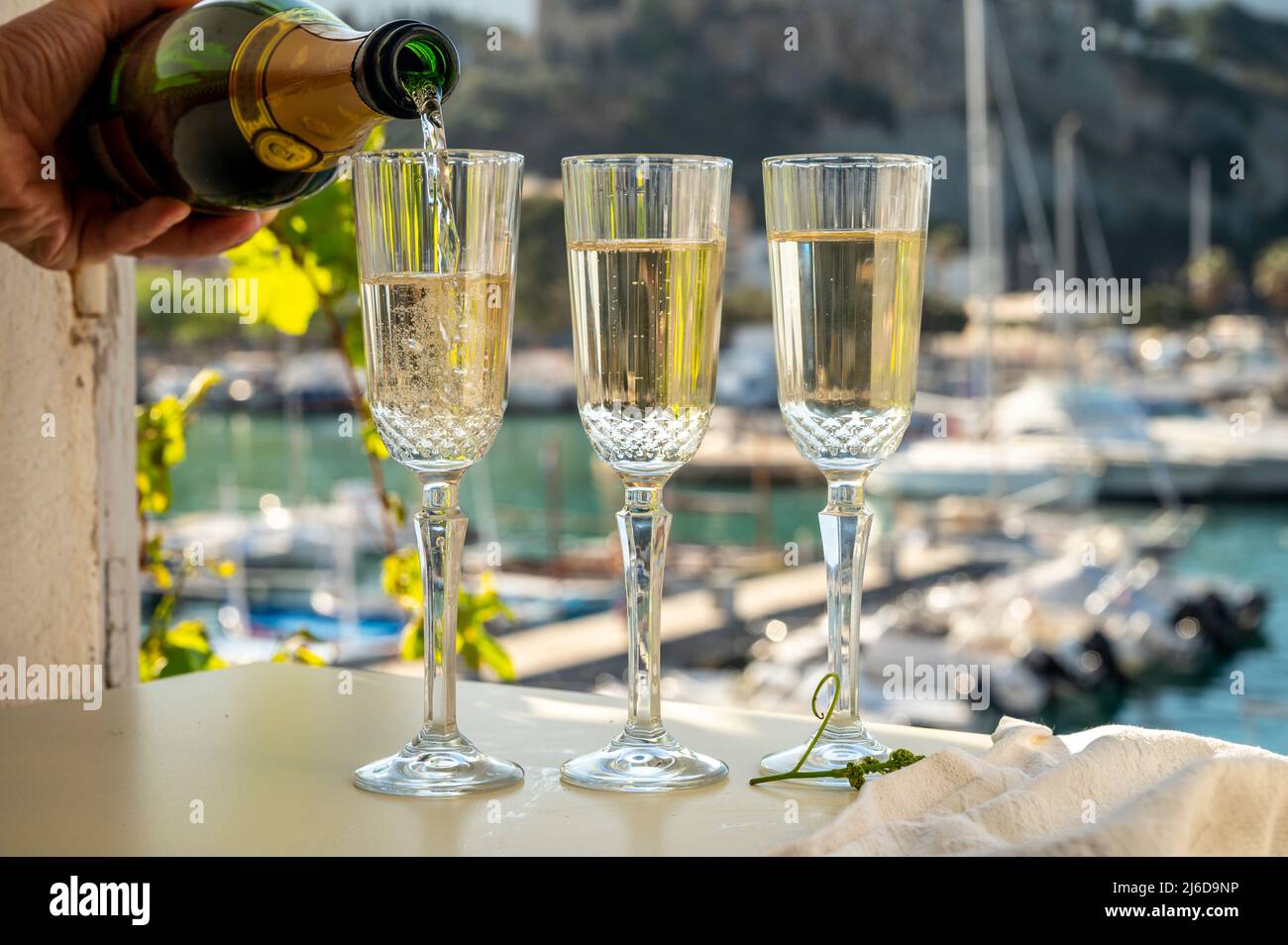 Versando in tre bicchieri di champagne francese spumante e vista sulle colorate barche di pescatori nel vecchio porto di Cassis, Provenza, Francia, estate Foto Stock