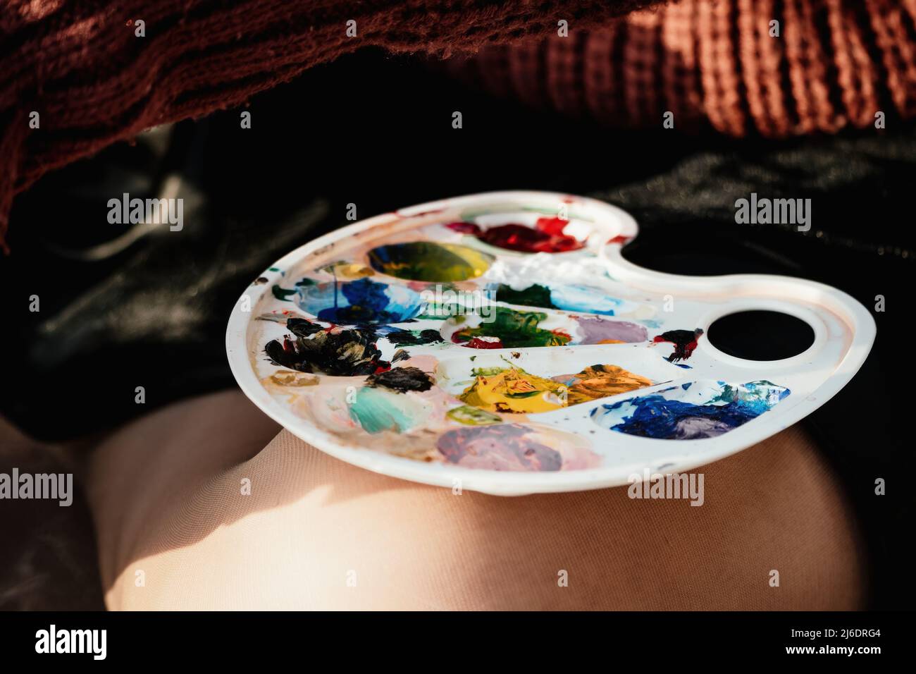Le mani di una donna che mescolano le vernici su una tavola della tavolozza. Preparazione alla verniciatura di un'immagine. Strumenti artistici. Il processo creativo. Foto Stock