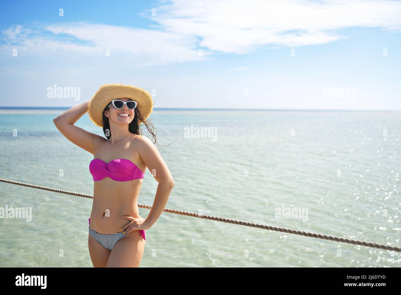 giovane donna sorridente in cappello di paglia sul pontile Foto Stock