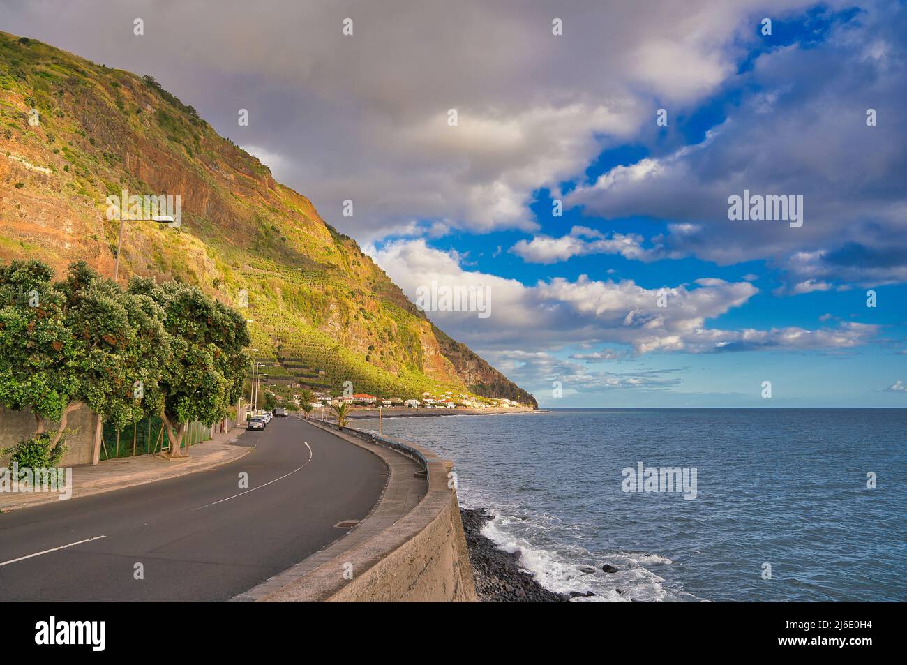 la strada costiera curva sullo sfondo le montagne e l'oceano atlantico con il bel cielo sull'isola di madeira, portogallo Foto Stock