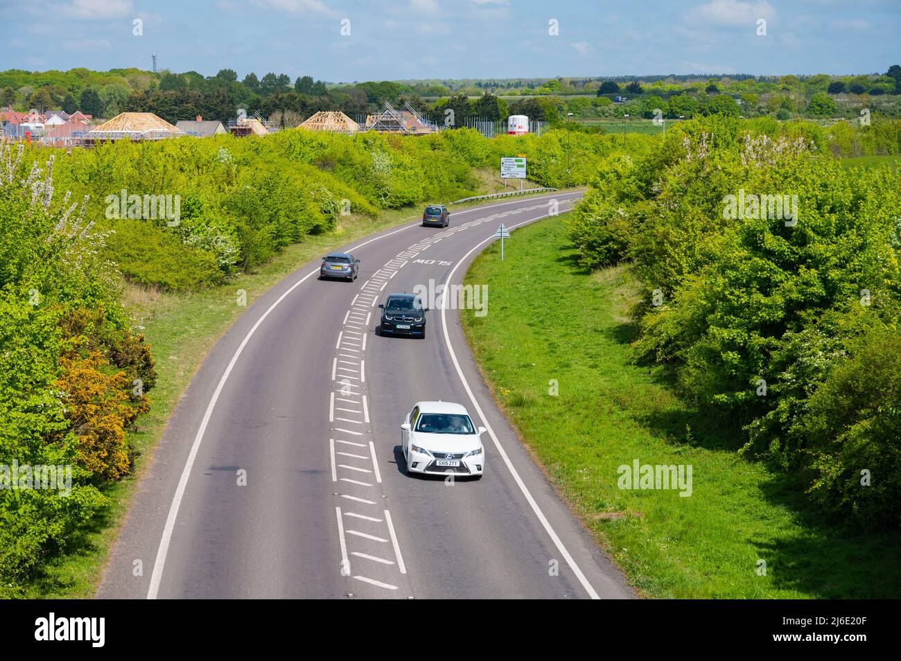 Le auto su A280 Angers aggirano attraverso la campagna con strisce diagonali bianche o chevron e linee bianche interrotte nel centro di West Sussex, Inghilterra, Regno Unito. Foto Stock