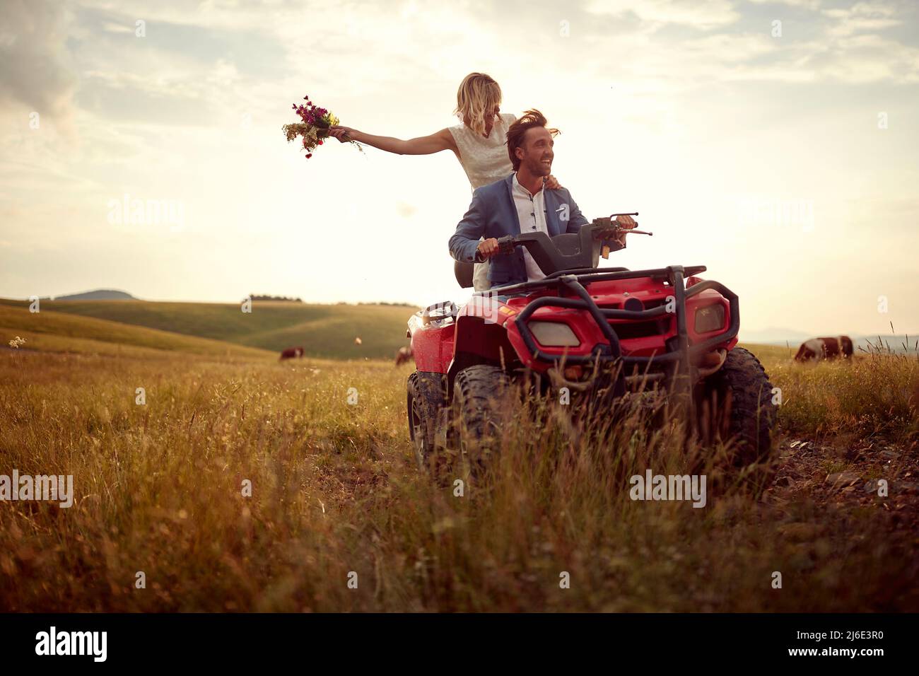Romantico sposi che guidano quad insieme nella natura; concetto di matrimonio rurale Foto Stock