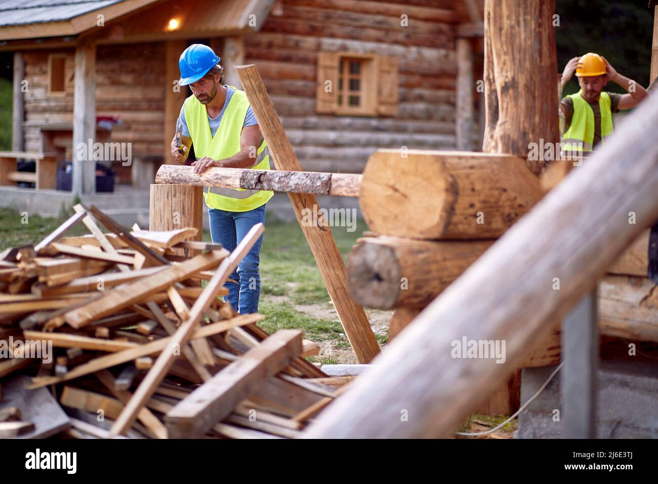 Costruttori che fanno un cottage in legno nella foresta in una bella giornata. Costruzione, costruzione, lavoratori Foto Stock