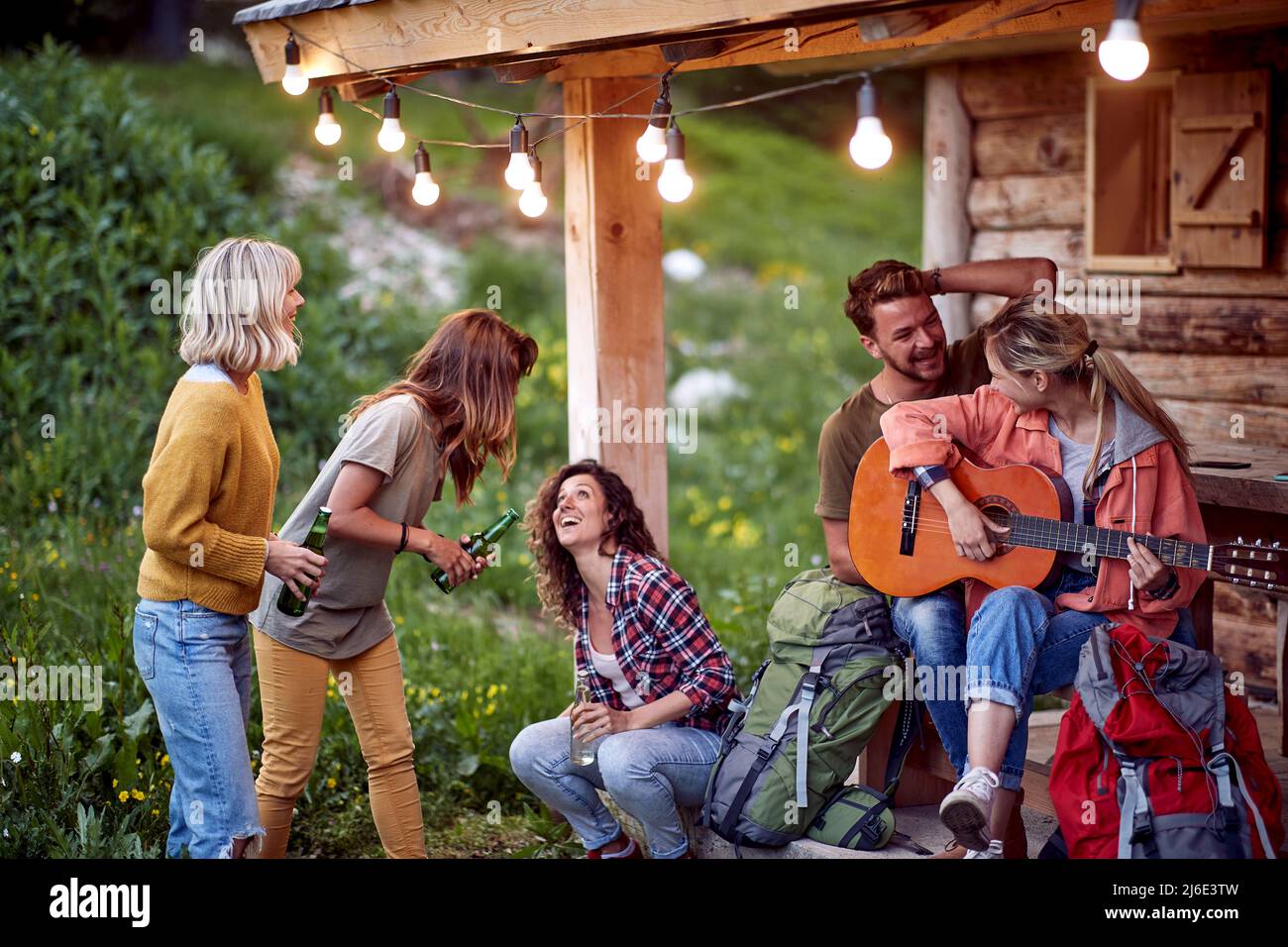 Giovani amici sorridenti che suonano la chitarra e bevono birra.persone in vacanza Foto Stock