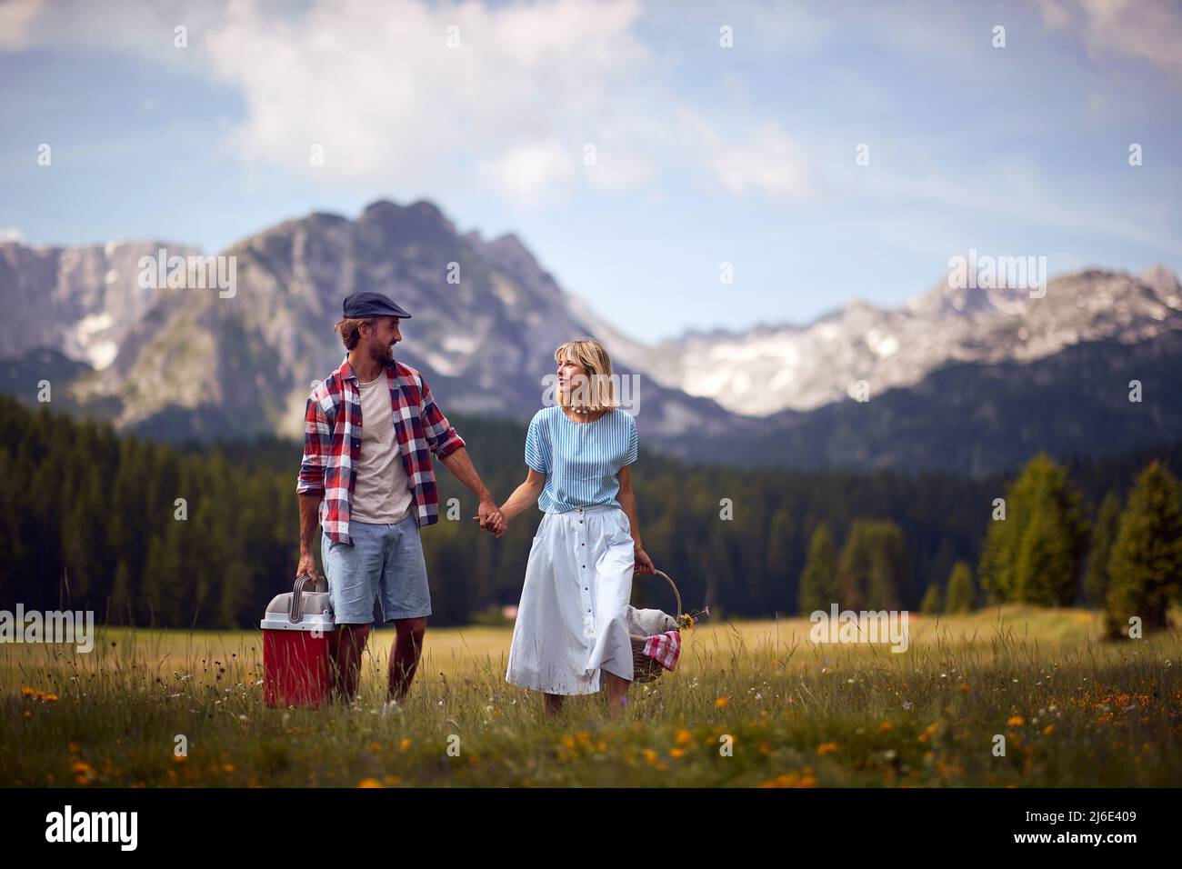 Coppia godendo picnic in nature.Young allegro sorridente coppia in amore tenendo le mani e camminando nella natura in una bella giornata. Foto Stock