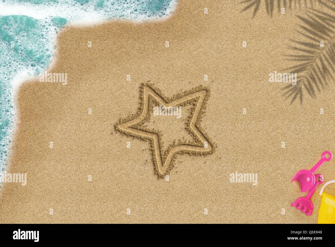 Stella disegnata su spiaggia sabbiosa, idea di ora d'estate, concetto di viaggio e vacanza, ombra di palma e onda di mare e composizione di giocattoli, vista dall'alto dell'icona della stella Foto Stock
