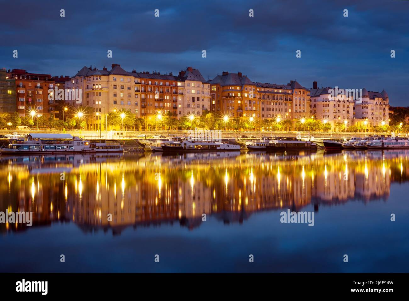 Blocco di vecchie case borghesi che si riflettono in un fiume di notte Foto Stock