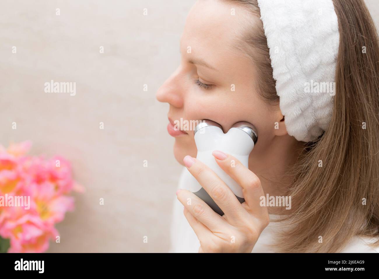 donna che si prende cura della pelle con un dispositivo di tonificazione a microcorrente Foto Stock